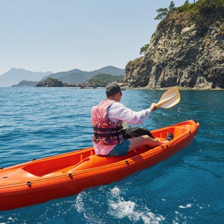 Boat kayaking near cliffs on a sunny day. Travel, sports concept. Lifestyle.